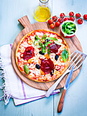 Pizza with cheese, bresaola, and rocket salad
