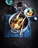 Stuffed pheasant in a casserole with carrots, potatoes, turnips and thyme