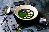 Nettle puree soup with quail eggs, violet blossoms and croutons