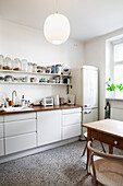 Weiße Küchenzeile mit Arbeitsplatte aus Holz, Regalbretter und Kühlschrank