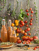 Bottled tomato sauce with herbs, surrounded by tomatoes and herbs