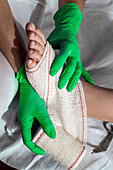 Nurse tying bandage on patient's foot