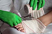 Nurse tying bandage on patient's foot