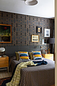 Double bed in bedroom - wallpaper with geometric pattern and artwork on wall