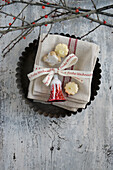 Baking dish with napkin, mixed biscuits and glass ornaments, holly branches behind it
