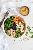 Gesunde Bowl mit Tofu, Grünkohl, Karotten, Sonneblumenkernen und Sesam