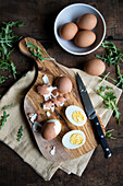 Hart gekochte Eier, teilweise geschält, auf Holzbrett