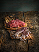 Rohes Rindfleisch und frische Tintenfische auf rustikalem Holzuntergrund