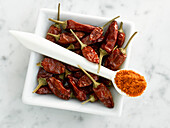 Bowl with dried chillies and spoon with chilli powder