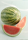 Wassermelone, ganz und Melonenviertel auf hellem Untergrund