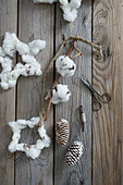 Girlande mit Stern aus Baumwolle und gekalkte Zapfen auf Holzuntergrund