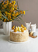 Easter cake with chocolate chicks next to a bouquet of mimosas