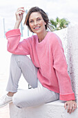 Frau in pinkfarbenem Pullover und weißer Hose