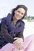 Long-haired woman in a dark coat with a sweater over her shoulders