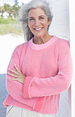 Gray haired woman in a pink sweater on the beach