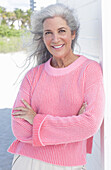 Grauhaarige Frau in pinkfarbenem Pullover am Strand