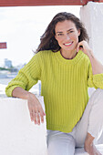 Long-haired woman in green-yellow knitted jumper and white trousers