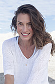 Long haired woman in white jumper on the beach