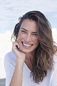 Happy long haired woman in white jumper on the beach