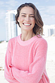 A happy, long-haired woman wearing a pink jumper