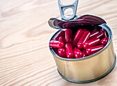 Can containing red capsules, conceptual image