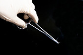 Gloved hand with needle holder forceps and suture