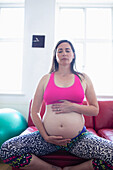 Pregnant woman meditating and holding baby bump