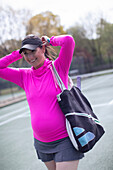 Smiling pregnant woman on tennis court
