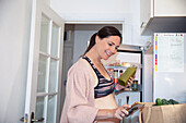 Pregnant woman in sports bra with groceries and smart phone