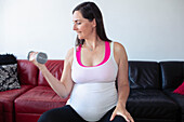 Pregnant woman working out with dumbbell at home