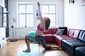 Pregnant woman stretching on yoga mat at home