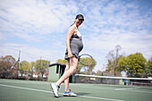 Happy woman in dress on sunny tennis court