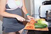 Pregnant woman slicing vegetables at cutting board