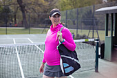Pregnant woman with bag on tennis court