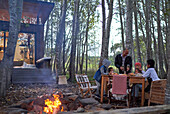 Family enjoying fireside dinner at table in woods