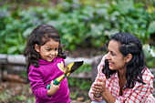 Happy mother and toddler daughter gardening with trowel