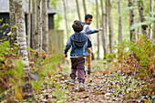 Brothers running on trail in woods