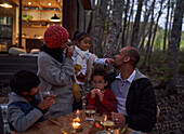 Family eating at table outside cabin in woods