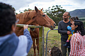 Family watching horse at fence
