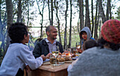 Happy family eating at table in woods