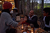 Family eating at candlelit table outside cabin