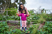 Happy mother and daughter harvesting carrot in garden