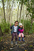 Brother and sister on swing in woods