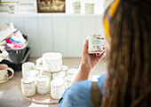 Young female artist painting ceramic mug in art studio