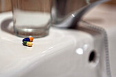 Glass of water and pills on bathroom sink