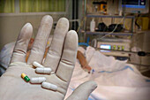 White latex gloved hand holding capsules