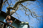 Young woman enjoying coffee on tree house balcony