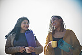 Happy women friends with yoga mats and coffee cups