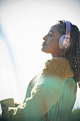 Young woman with headphones basking in sunshine