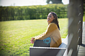 Happy woman with yoga mat on sunny bench